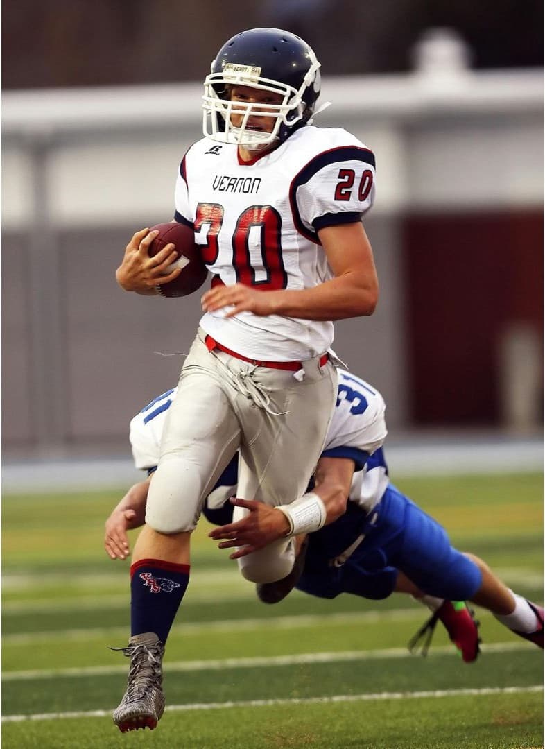Football running back evading a tackle in mid-air